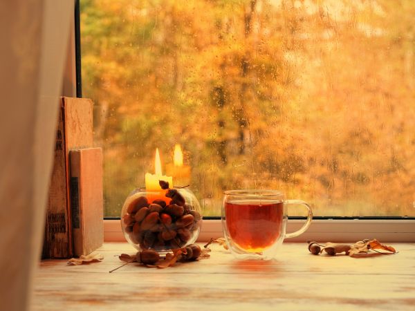 Udsigt til efterår fra et vindue med lys og en tekop