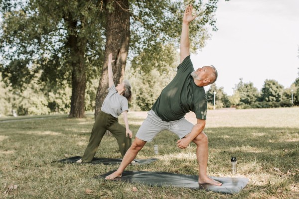 En mand og en kvinde i overgangsalderen dyrker yoga i naturen